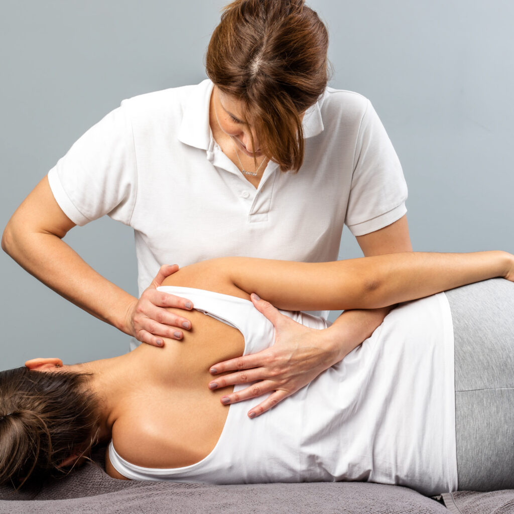 Female therapist manipulating shoulder blade on young female patient.